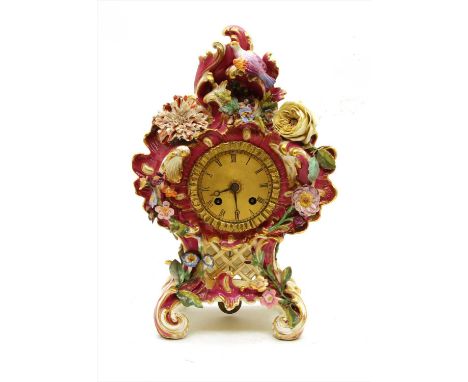 A Coalport porcelain mantel clock, ornately decorated with scrolls and applied flowerheads on a claret ground, 30cm high