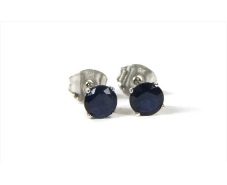 A pair of white gold single stone sapphire stud earrings, with a circular mixed cut sapphire, claw set to a wire collet, with