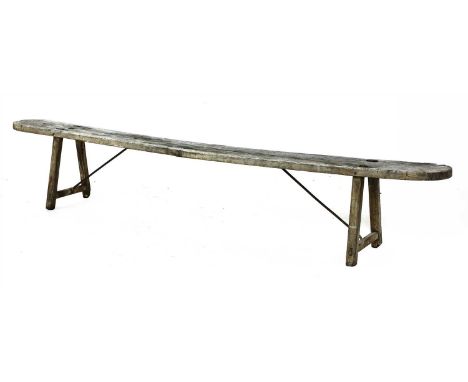 A rustic plank-topped bench, with splaying supports to either end, with iron stretchers, 253cm wide, 24cm deep, 46cm high