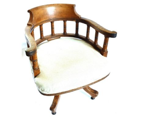 LATE VICTORIAN OAK SWIVEL CHAIR, raised on four splayed legs with casters, bearing a brass makers plaque to the underside for