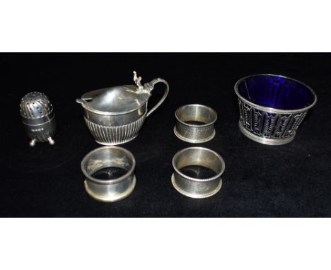 FIVE ITEMS OF SILVER WARE  Comprising a mustard with glass liner (liner cracked) a pepperette, a pair of Victorian napkin rin