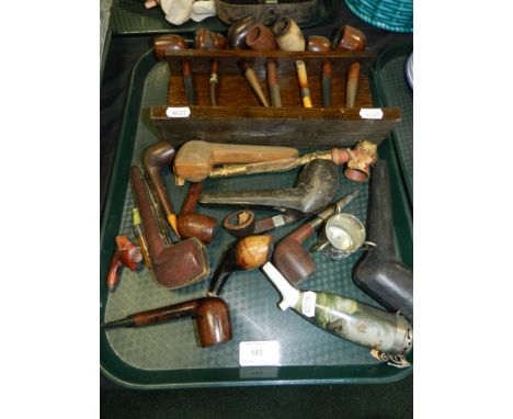 An oak pipe rack containing a quantity of pipes together with a further small selection of loose pipes including a figural ex