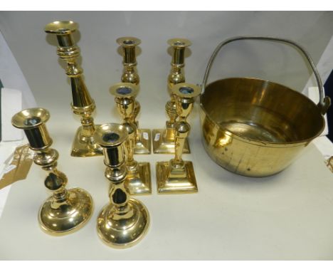 Three pairs of brass candlesticks, a further single brass candlestick and a brass swing handled preserve pan