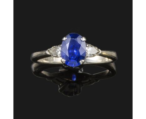 A sapphire and diamond three stone ring, the oval shaped sapphire set in two pear shaped shoulder diamonds in platinum, size 