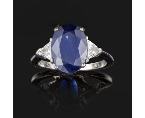 A sapphire and diamond three stone ring, the oval-shaped sapphire weighs approximately 4.90cts, flanked with triangular-shape