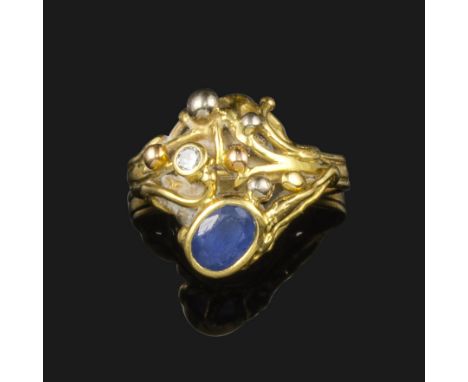 A sapphire and diamond cluster ring by Martin White, set with an oval-shaped sapphire and a circular-cut diamond in abstract 