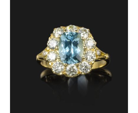 An aquamarine and diamond cluster ring, the cushion-shaped aquamarine is set within a surround of round brilliant-cut diamond