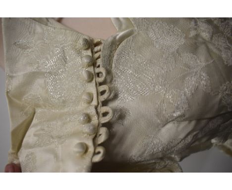 A late 1950s cream wedding dress and veil, dress having full length sleeves with buttons to cuffs and button fastening to rev