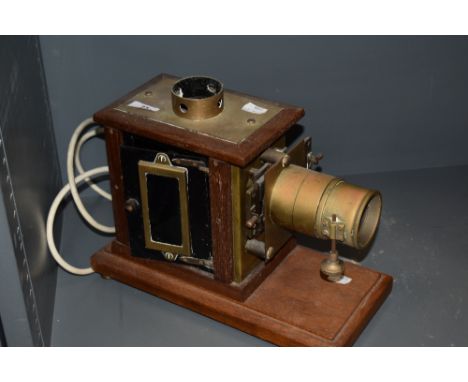 A late Victorian magic lantern slide projector having a brass and oak case having later been adapted to electric.