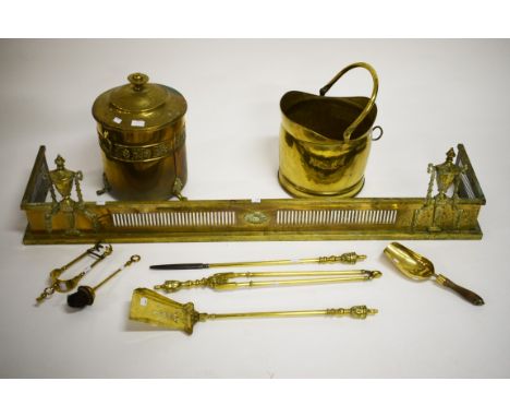 AN EDWARDIAN PIERCED BRASS FENDER, with two urn finials. 56" (143cm) wide. Togetherwith two brass coal buckets. AND a set of 