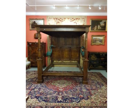 A LARGE SEVENTEENTH CENTURY STYLE OAK CANOPY BED, with panelled roof and back. The back with a moulded shelf, on corbel suppo