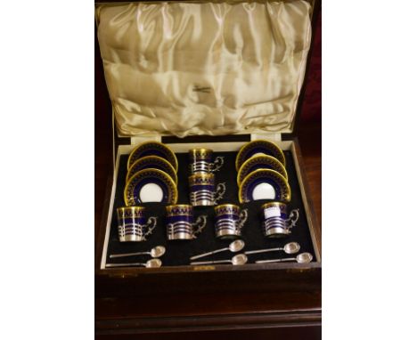 A FINE CASED SET OF SIX SILVER MOUNTED COFFEE CUPS AND SAUCERS and a set ofsix matching silver coffee spoons. The dark blue a