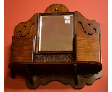 A SMALL EARLY TWENTIETH CENTURY CARVED AND PIERCED OAK MIRROR WALLBRACKET, with two compartments and a D-shaped shelf. 17" (4