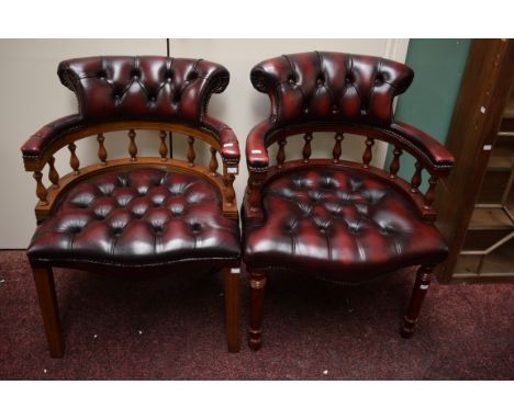 A PAIR OF GOOD QUALITY MODERN OFFICE DESK CHAIRS, each with a button seat andrailed back, covered in burgundy hide. On front 