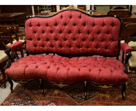 AN UNUSUAL EBONISED HIGH BACK SETTEE. Ornate brass mounts. Arched button backabove a conforming serpentine fronted seat. Cove