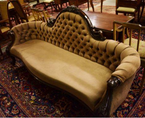 A VICTORIAN SERPENTINE SHAPED MAHOGANY SETTEE, with arched and button back.Conforming armrests and padded seat. On front cabr