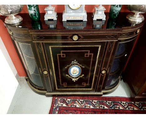 A VICTORIAN EBONISED AND BRASS MOUNTED CREDENZA. Breakfront outline, applied withporcelain panels, each within a gilt brass f