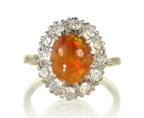 An opal and diamond cluster dress ring in 18ct yellow gold set with an oval cabochon cut opal surrounded by a border of round