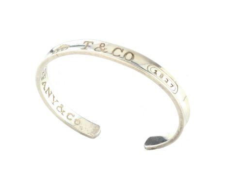 TIFFANY A vintage sterling silver bangle by Tiffany & Co dated 1997. The incomplete band with concave surface featuring Tiffa