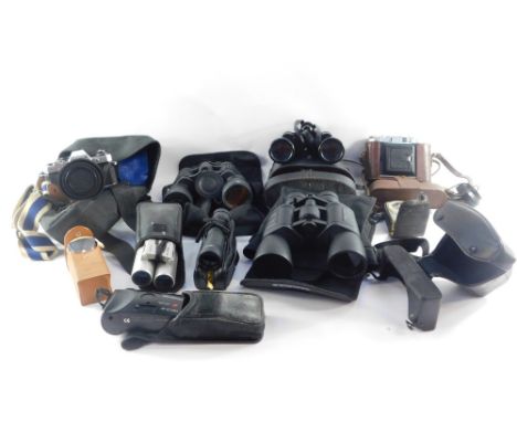 A group of camera and binocular equipment, comprising an Olympus OM10, Lokina SD 1-4-5.6 lens, Praticka travel binoculars, a 