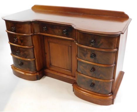 A Victorian mahogany inverted bow front desk, with one central drawer above a cupboard door, flanked by eight short drawers, 