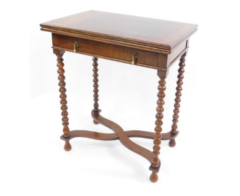 A Carolean style oak fold over card table, with a single frieze drawer, having brass pear drop handles, on bobbin turned supp