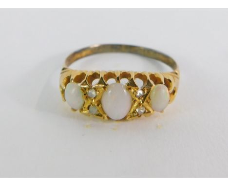 An 18ct gold diamond dress ring, the marquise shaped top set with three oval opals and four tiny diamonds on a raised claw se