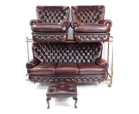 A maroon leather button back Chesterfield sofa suite, comprising three seater sofa, two matching armchairs and a footstool, e