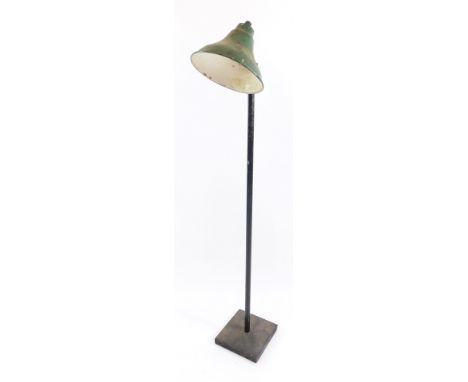 An industrial mid century standard lamp, with green metal shade, on a black metal pole and square base, 140cm high.