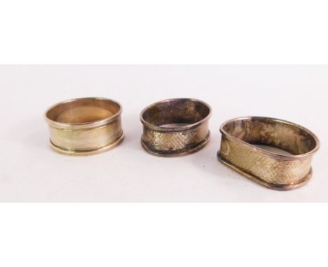 Three silver napkin rings, to include an oval engine turned decorated napkin ring with vacant shield panel, circular napkin r