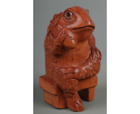 A hand carved hardwood netsuke of a sitting frog  