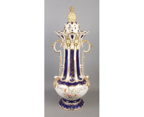 A large ceramic lidded, twin handle jar decorated with floral motifs and topped with pineapple finial.  Chips around bottom e