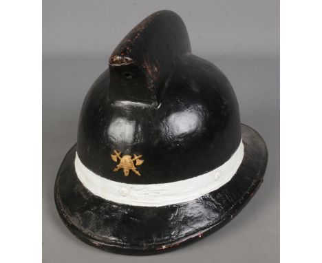 A painted leather fireman's helmet baring axe &amp; helmet insignia.  
