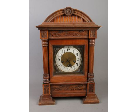 An oak cased mantle clock featuring J Unghans movement and carved foliage motifs. With key.  