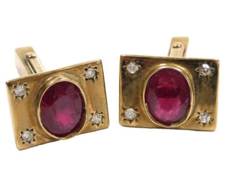 A pair of ruby and diamond set cufflinks, each set with an oval cut ruby, flanked by pairs of diamonds, in yellow metal, stam