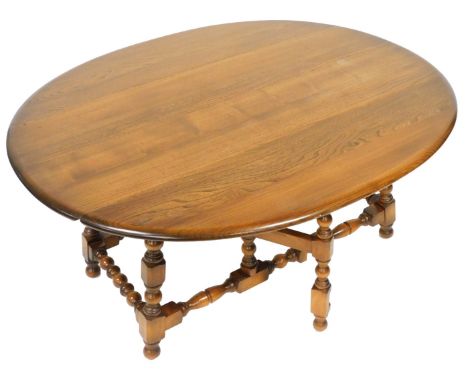 An Ercol dark elm drop leaf coffee table, raised on turned supports, united by a turned box stretcher, 49cm high, 106.5cm wid