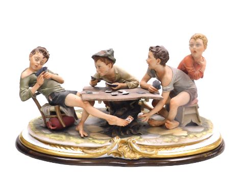 A Capodimonte porcelain figure group, modelled as "The Cheats" by Bruno Merli, depicting four boys playing cards, raised on a
