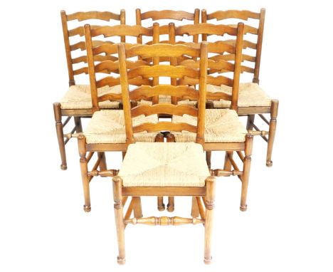 A set of six oak ladder back dining chairs, each with a rush seat, on turned legs and stretchers. 