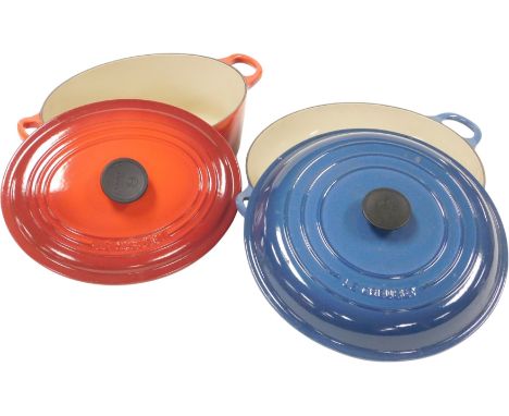 A Le Creuset red enamel twin handled casserole dish, together with a blue enamel frying pan and cover.
