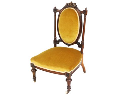 A Victorian walnut nursing chair, with a gold upholstered padded back and seat, on turned legs with ceramic castors. 