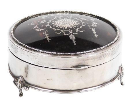 A George V silver and tortoiseshell dressing table box, of circular form, the hinged lid with pique decoration of floral sunb