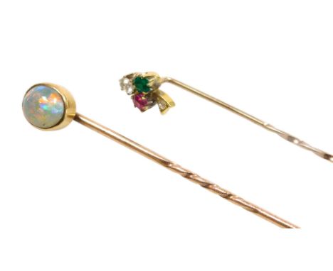 An emerald ruby and diamond stick pin, modelled as a three leaf clover, and an oval opal stick pin, both in yellow metal, 2.6