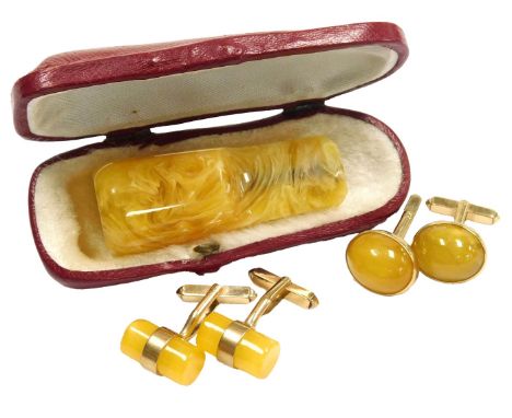 A pair of yellow amber cufflinks, of cylindrical form, in yellow metal mounts, together with a pair of cabochon amber cufflin