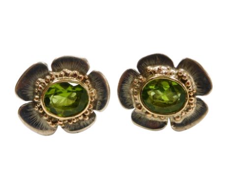 A pair of peridot flowerhead cufflinks, the oval cut stones in white metal.