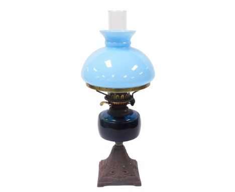A late 19thC Duplex oil lamp, with a blue glass reservoir and cast iron foliate embossed base, with chimney and turquoise gla