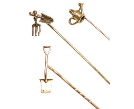 Three gardening related tie pins, formed as watering can, crossed trowel and fork, and a spade, in yellow metal, 2.8g.