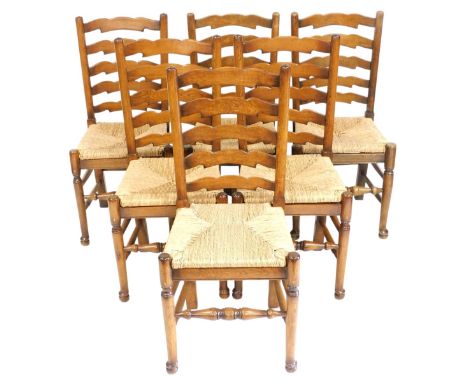 A set of six oak ladder back dining chairs, each with a rush seat, on turned legs and stretchers. 