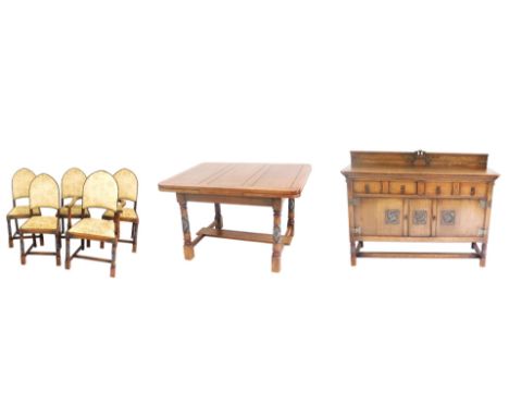 An early 20thC oak dining suite, comprising a sideboard, with a castle carved back, and four frieze drawers, over two panelle