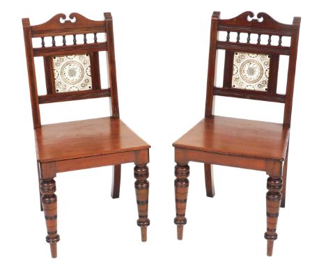 A pair of late 19thC mahogany hall chairs, each with a black printed Minton style tile inserted to the back, a solid seat, on