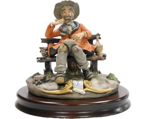 A Capodimonte porcelain figure of a tramp, by Sartori, modelled seated on a bench, eating spaghetti, raised on an oval wooden